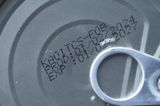 Inspecting the expiry date and production code on a canned food product.