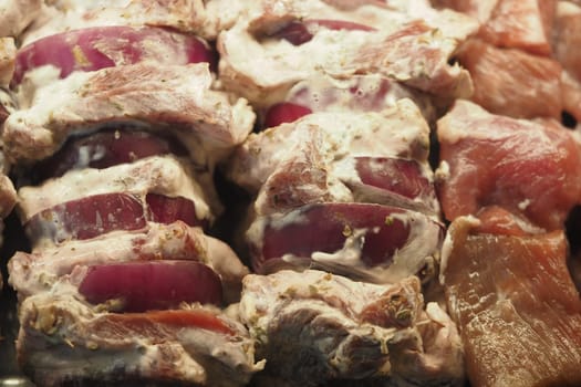 Juicy meat and onion skewers ready for grilling outdoors during summer.