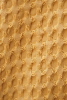 A close-up view of a warm yellow fabric featuring a distinct honeycomb texture.