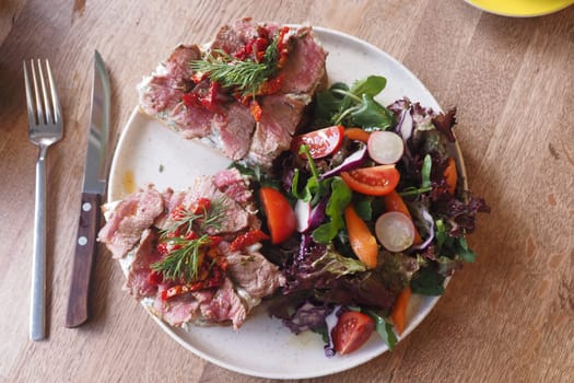Tender meat with herbs alongside a vibrant fresh vegetable salad.