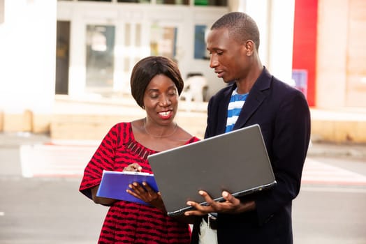 African adult business partners looking for a laptop investment project while smiling, new opportunities
