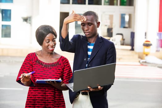 beautiful african adult woman and man working together on a project using a laptop and files outdoors
Business, teamwork and staff concept