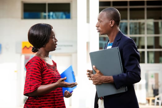 man and a beautiful adult woman as business partners discussing business holding computer and folder on the outside