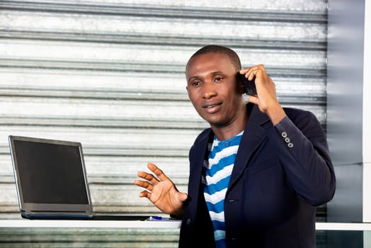 Happy professional african adult business man using a cell phone talking on the phone and smiling in the city center