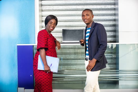 businessman and businesswoman standing smiling in the street holding in hand folder and computer