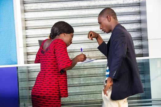 beautiful african adult business woman using a document, signing a contract of employment while smiling