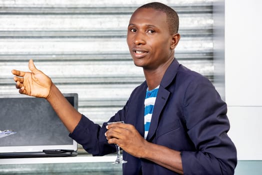 handsome african adult businessman wearing a jacket is going to enjoy a glass of red wine outdoors