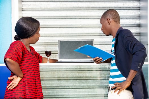 handsome businessman and businesswoman looking at computer together in the street outdoors