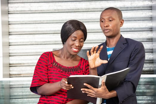 Two young business people walking down the street, man showing the project document to the adult business woman