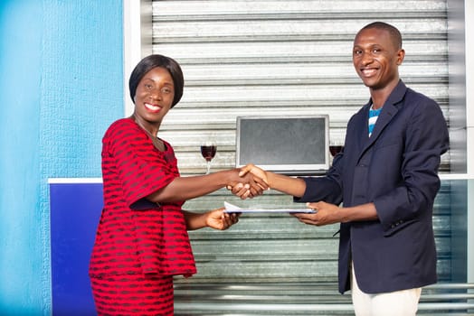 Professional business woman and man in formal suit shaking hands outside to make an agreement exchanging documents while smiling