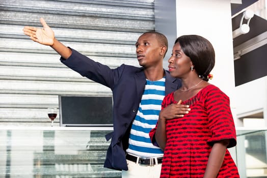 African man wearing a jacket pointing finger pointing at the direction of the businesswoman holding hands on the heart while smiling