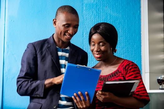 businessman and businesswoman discussing the next project together holding in hand each a document in the street