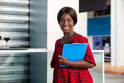 beautiful adult businesswoman dressed in red loincloth holding a document in hand in the street smiling