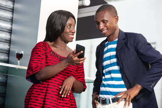 beautiful african businesswoman is showing a text message using the mobile phone to her colleague while smiling