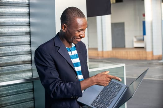 Handsome adult businessman pointing to show a laptop while being happy on the street