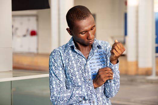 young businessman standing in shirt loincloth outdoors adjusting his button.