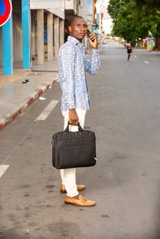 young businessman standing outdoors talking on mobile phone looking away.