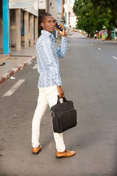 young businessman standing outdoors talking on the phone while looking at the profile camera.