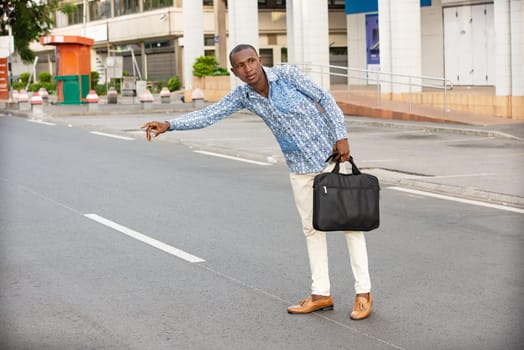 young businessman standing by the roadside beckoning to a car .