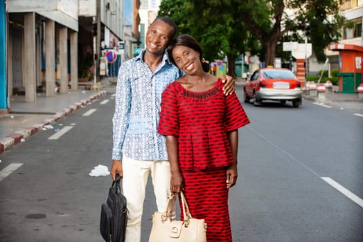 beautiful adult businesswoman dressed in red loincloth walking together with her partner wearing a shirt and jeans on the street being happy