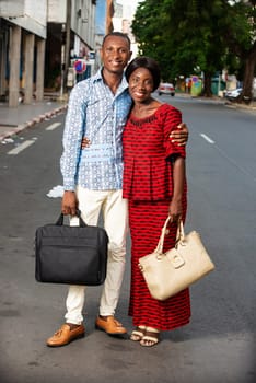 beautiful adult businesswoman dressed in red loincloth walking with her partner wearing a shirt jeans holding hands together on the street being happy