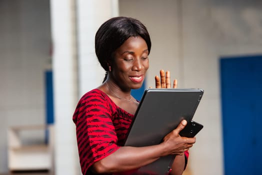 beautiful african businesswoman dressed in red loincloth standing in the street holding in hand a laptop