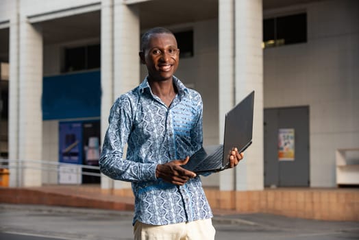 young african american man working standing up using a computer smiling in the street
