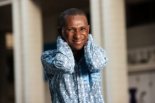 African businessman suffering from neck pain and feeling tired, exhausted, stressed by massaging painful neck with hands.