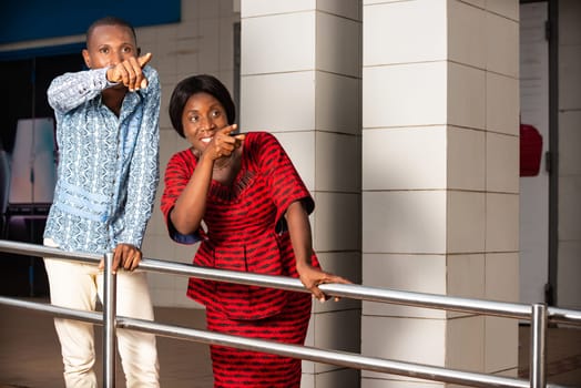 two business people in traditional clothes standing outside showing something smiling.