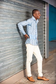 African adult man standing with back pain on the street