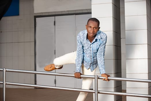 young man in traditional clothes jumping iron bar and looking at camera smiling.