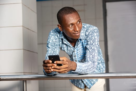 Portrait of young adult businessman using a mobile phone while looking away at the street smiling