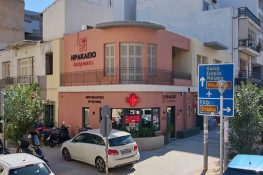 Crete.Greece - april 13, 2025: A modern pharmacy in Heraklion with a blue and wooden facade, featuring signage in Greek and a green cross, offering a glimpse into local urban life.