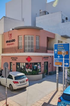 Crete.Greece - april 13, 2025: A Greek pharmacy with vibrant signage and architectural features that blend traditional elements with modern utility in Heraklion under sunny skies.