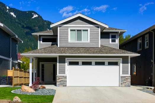 A perfect neighbourhood. Brand new house on the final stage of construction. Family house on snow mountain and blue sky background