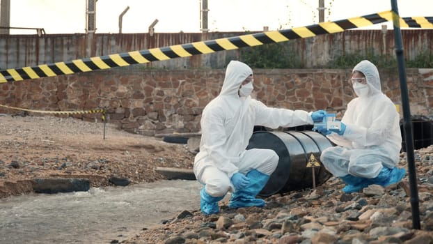 Ecologist sampling water from the river with test tube, Scientist or Biologist in a protective suit and protect mask collects sample of waste water from industrial for analyze, problem environment