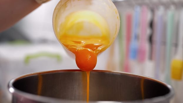 Yellow yolks are added in metal stand mixer bowl. Whipping eggs for baking. Baking, recipes, sponge cake, cookies, desserts. Omelette, breakfast concept. Quality