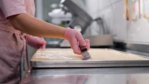 Confectioner woman working at kitchen. Spreading almond batter to smooth, silky texture. Delicate pastries - macarons, tarts, gluten-free bakes.