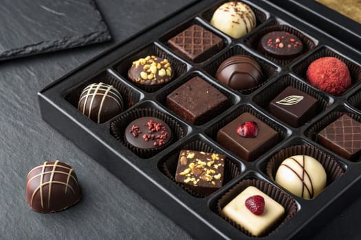 A carefully arranged collection of handmade chocolates showcases various flavors and decorations. The neat presentation highlights attention to detail and craftsmanship, making it an inviting treat.