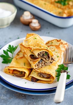 Savory crepes filled with mushrooms and herbs are beautifully arranged on a plate. Fresh parsley garnishes the dish, complementing the meals warm tones. Perfect for a cozy gathering or meal.