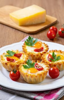 A plate holds four golden pastry cups filled with eggs, cherry tomatoes, and parsley. Fresh ingredients provide a colorful presentation, ideal for breakfast or brunch gatherings.