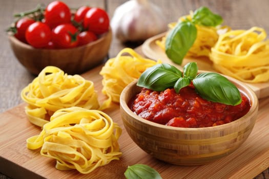Freshly made fettuccine is displayed with a vibrant tomato sauce and garnished with basil leaves. Cherry tomatoes and garlic sit nearby, adding to the rustic culinary atmosphere of the kitchen.