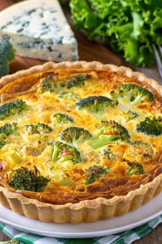 A savory tart featuring a rich filling of broccoli and melted cheese rests on a white plate.
