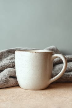 Rustic ceramic mug with speckled surface on soft woven fabric. Ideal for lifestyle branding, cozy scenes, autumn themes, coffee rituals, or product display in warm tones