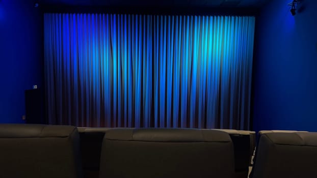 Empty Cinema Theater With Blue Curtains and Comfortable Seating. A serene theater interior showcasing blue curtains and modern seating, evoking a calm ambiance.