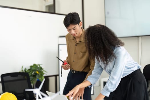In an innovative office, a man and a woman analyze renewable energy models together, highlighting collaboration and the importance of sustainability in business.