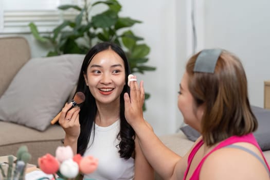 A fun makeup tutorial session at home, where one woman learns how to apply blush and eye makeup, enhancing her beauty while enjoying the process.