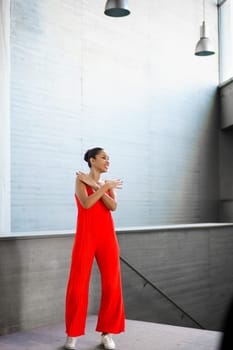 A stylish and fashionable young woman poses confidently in a strikingly beautiful red outfit, truly embodying modern elegance within a chic and vibrant space that radiates sophistication and grace