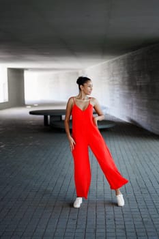 A skilled dancer in a striking red jumpsuit performs with grace against a stunning backdrop, blending style and artistry to create a captivating spectacle that mesmerizes all viewers
