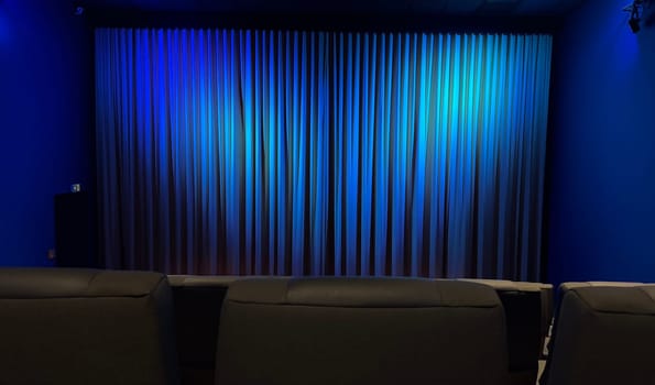 Empty Cinema Theater With Blue Curtains and Comfortable Seating. A serene theater interior showcasing blue curtains and modern seating, evoking a calm ambiance.